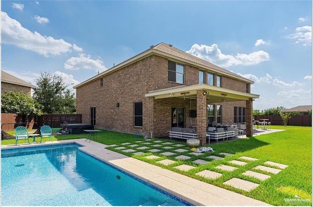 rear view of property featuring a lawn, a fenced in pool, outdoor lounge area, and a patio