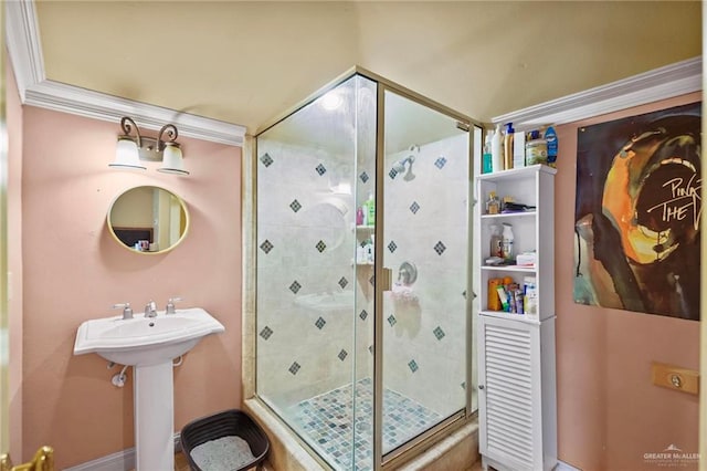 bathroom with a shower with shower door, ornamental molding, and sink