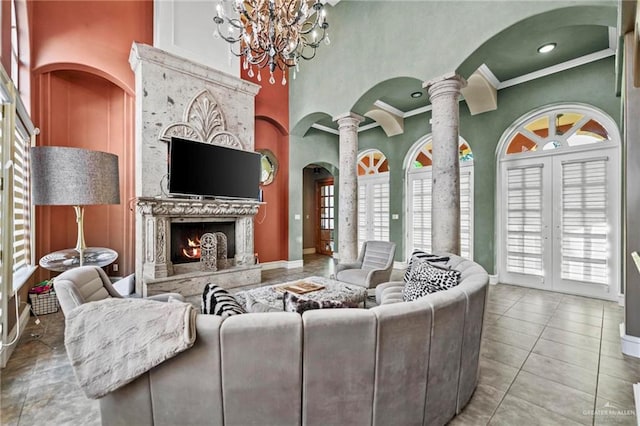 tiled living room featuring ornate columns, an inviting chandelier, a premium fireplace, a towering ceiling, and ornamental molding