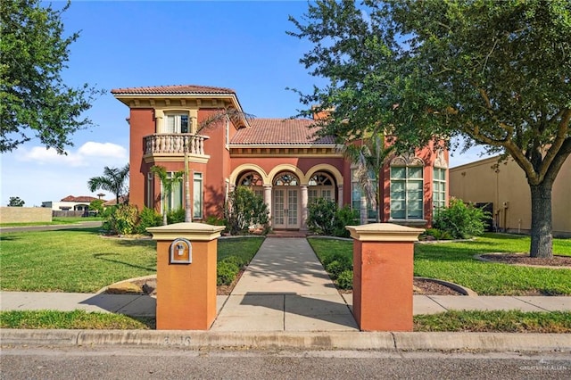 mediterranean / spanish-style home featuring french doors, a balcony, and a front lawn