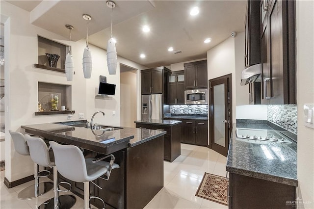 kitchen with backsplash, hanging light fixtures, sink, stainless steel appliances, and extractor fan