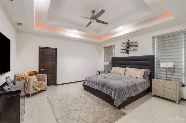 tiled bedroom with a raised ceiling and ceiling fan