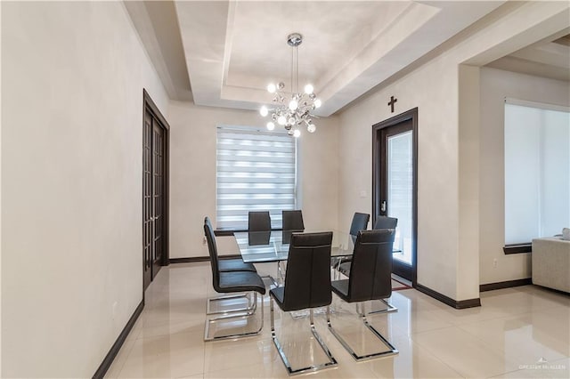 tiled dining room featuring a tray ceiling and an inviting chandelier