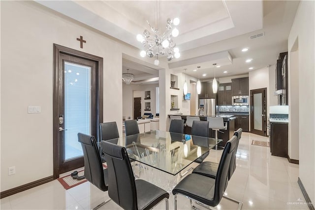 dining space with light tile patterned flooring, a tray ceiling, and an inviting chandelier