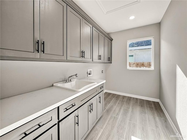 laundry room featuring washer hookup, sink, cabinets, and light wood-type flooring