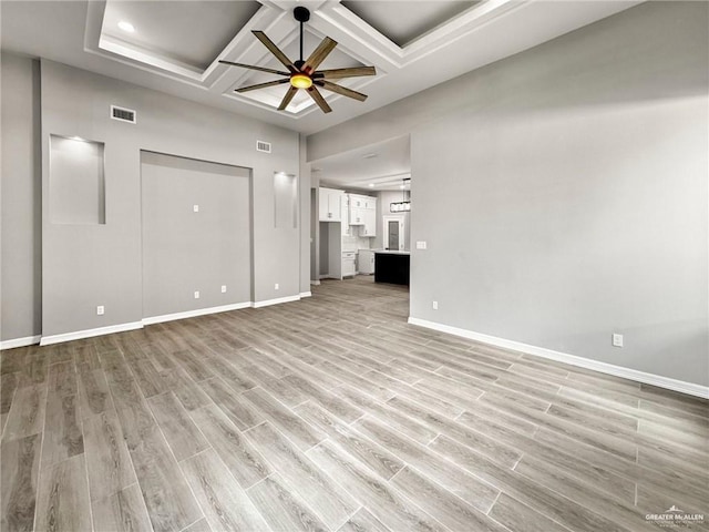 unfurnished living room with ceiling fan, coffered ceiling, light hardwood / wood-style floors, and a towering ceiling