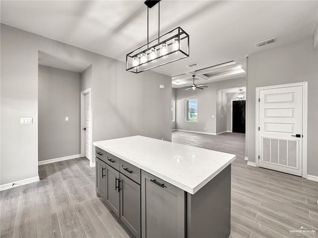 kitchen with gray cabinetry, hanging light fixtures, a center island, ceiling fan, and light hardwood / wood-style flooring