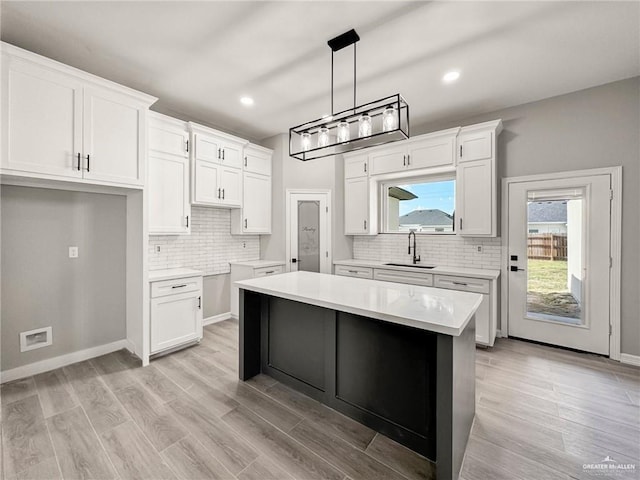 kitchen featuring white cabinetry, sink, pendant lighting, and a center island