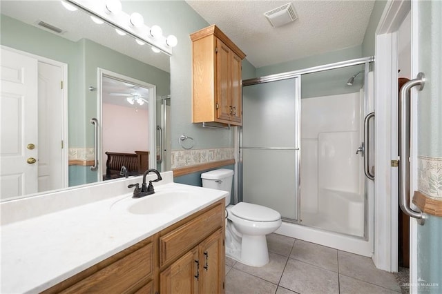 bathroom featuring a shower with shower door, vanity, toilet, tile patterned floors, and a textured ceiling