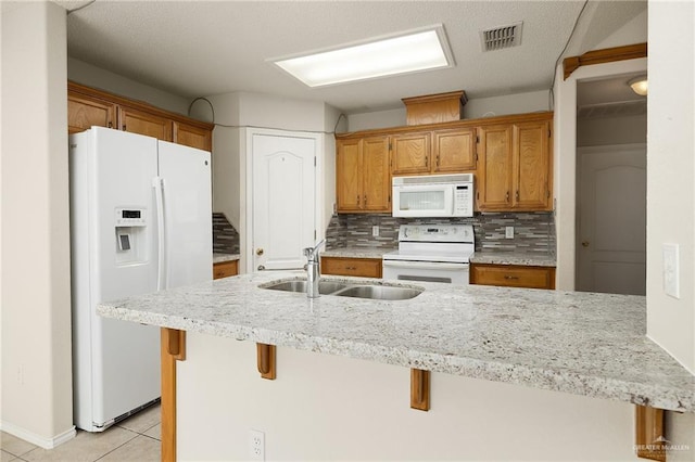 kitchen with light tile patterned flooring, sink, a kitchen breakfast bar, white appliances, and backsplash