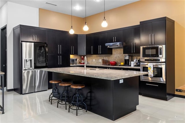 kitchen featuring sink, a breakfast bar area, decorative light fixtures, appliances with stainless steel finishes, and decorative backsplash