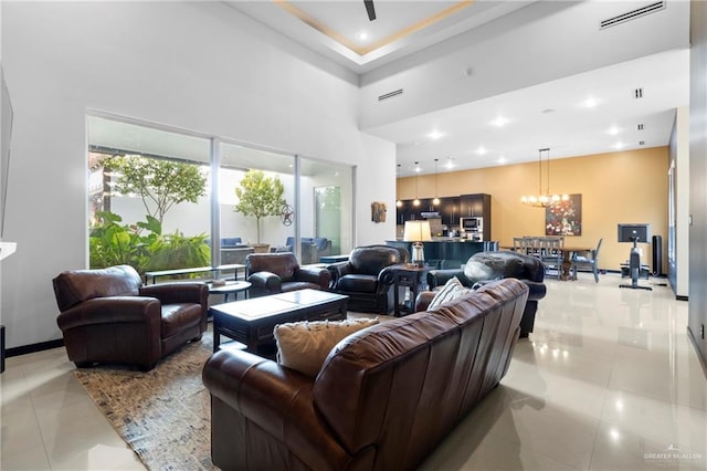 living room featuring a towering ceiling, light tile patterned floors, and an inviting chandelier