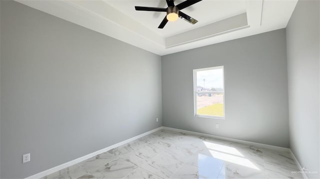 empty room featuring a tray ceiling and ceiling fan