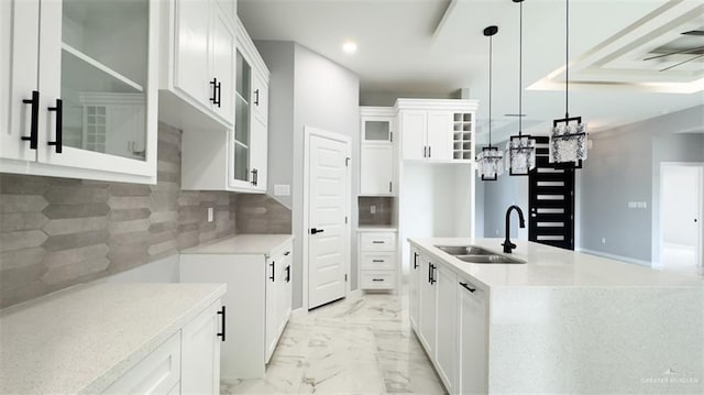 kitchen featuring sink, white cabinetry, pendant lighting, an island with sink, and tasteful backsplash