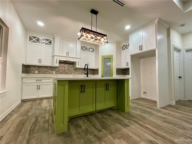 kitchen featuring white cabinetry, an island with sink, green cabinets, and pendant lighting