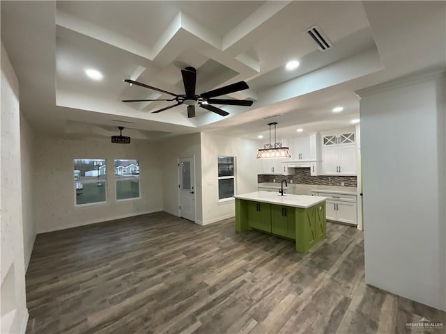 kitchen with dark hardwood / wood-style floors, pendant lighting, white cabinetry, an island with sink, and green cabinets