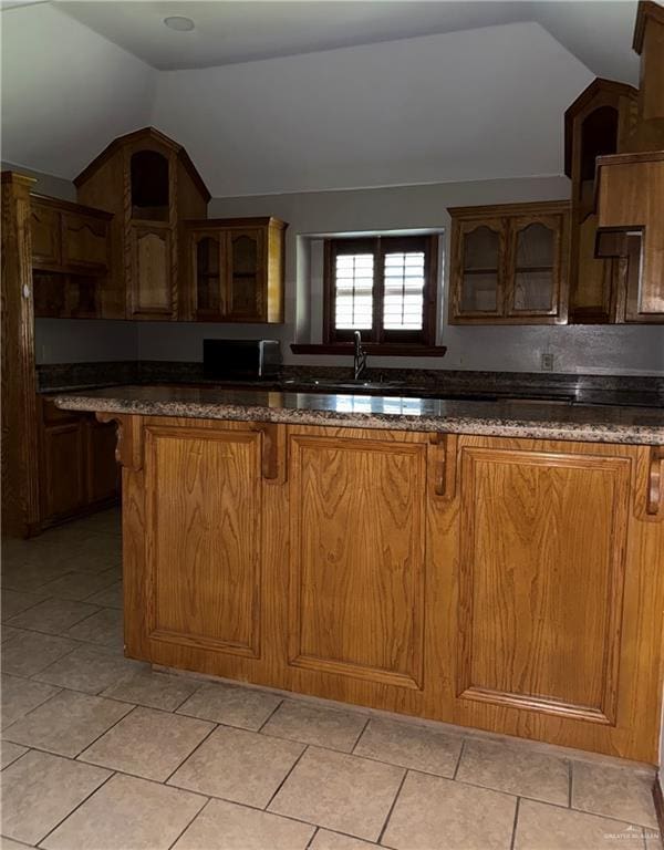 kitchen featuring a kitchen breakfast bar, vaulted ceiling, and glass insert cabinets