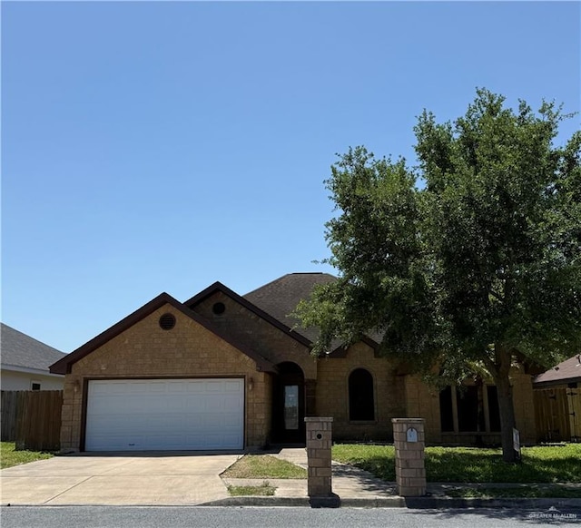 view of front of house with fence, an attached garage, and concrete driveway