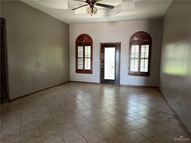 unfurnished room featuring tile patterned flooring, a ceiling fan, baseboards, and a wealth of natural light