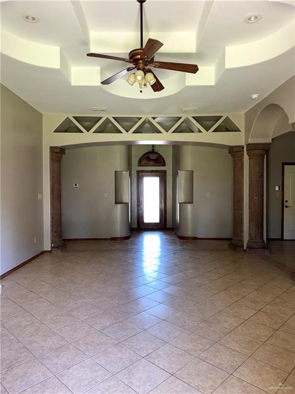 spare room featuring a ceiling fan, decorative columns, light tile patterned floors, and a raised ceiling