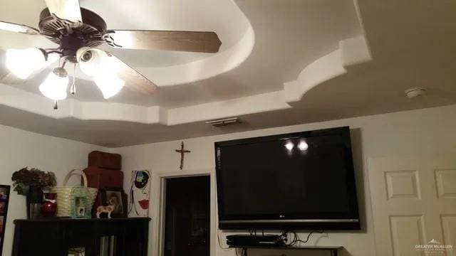 interior details featuring a tray ceiling and ceiling fan