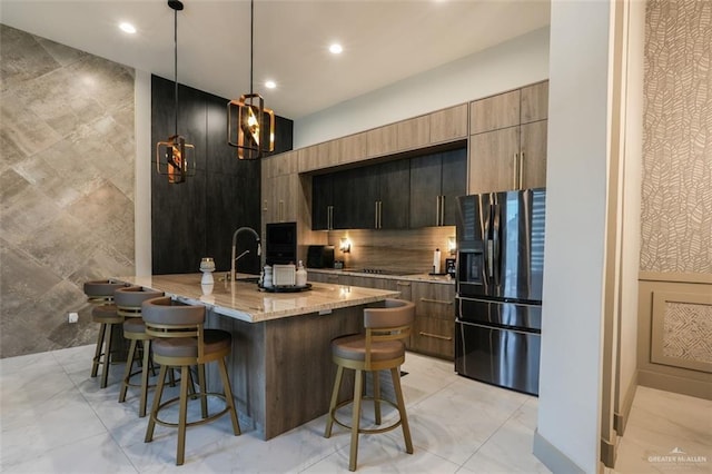 2511 Wisteria St, Mission, TX 78574 - kitchen featuring refrigerator with ice dispenser, a breakfast bar, modern cabinets, black electric stovetop, and light stone countertops