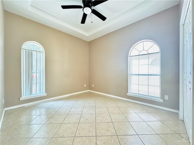 tiled spare room with a tray ceiling and ceiling fan