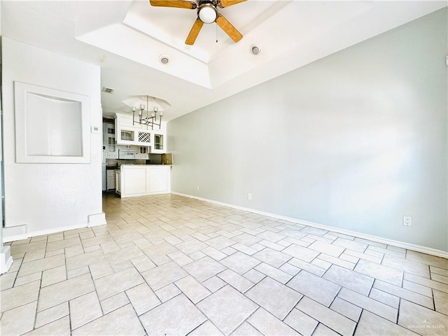 unfurnished living room featuring ceiling fan with notable chandelier and a raised ceiling