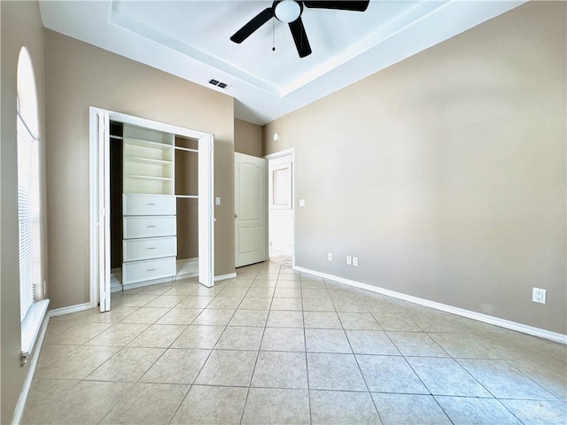 unfurnished bedroom with ceiling fan, light tile patterned floors, and a tray ceiling