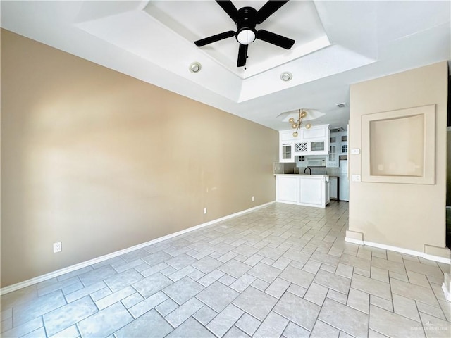 unfurnished living room featuring ceiling fan and a raised ceiling