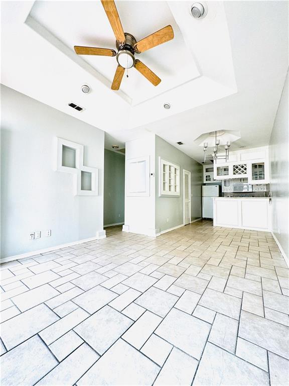 unfurnished living room with ceiling fan, light tile patterned floors, and a raised ceiling