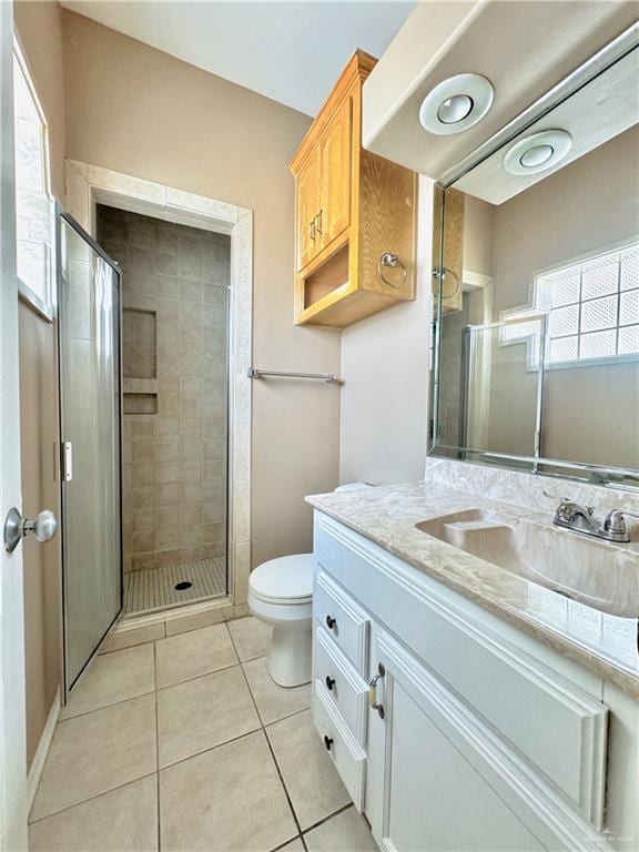 bathroom with vanity, a shower with door, toilet, and tile patterned floors