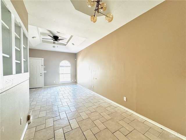 unfurnished room with ceiling fan with notable chandelier and a raised ceiling