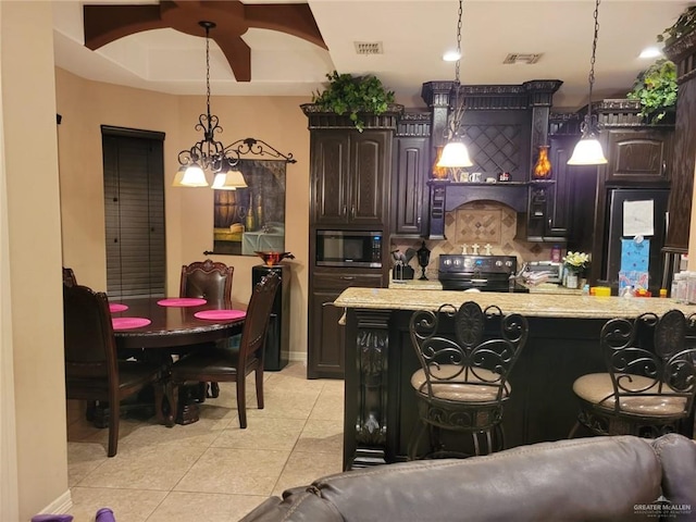 kitchen featuring electric range, a breakfast bar, dark brown cabinetry, and hanging light fixtures