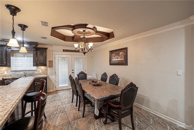 dining space featuring a chandelier, a raised ceiling, crown molding, and french doors