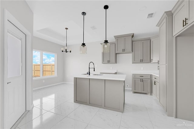 341 Leon Ave, Elsa, TX 78543 - kitchen with gray cabinets, light marble finish floors, a center island with sink, a chandelier, and hanging light fixtures