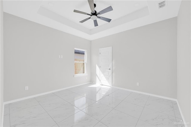 341 Leon Ave, Elsa, TX 78543 - empty room featuring light marble finish flooring, a raised ceiling, and a ceiling fan