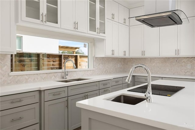 kitchen with sink, decorative backsplash, gray cabinets, and range hood