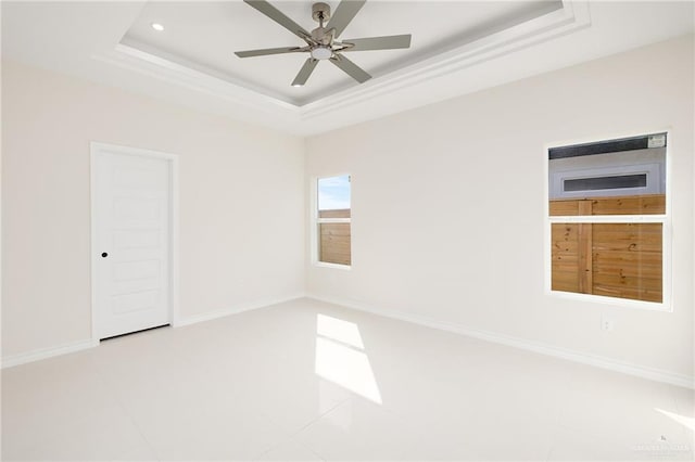 empty room featuring a raised ceiling and ceiling fan