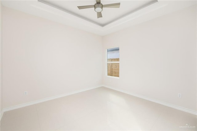 spare room with a tray ceiling and ceiling fan