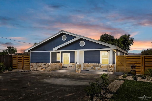 view of front of home featuring a patio area, stone siding, and fence