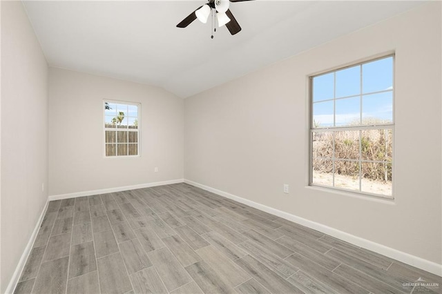 spare room featuring baseboards, vaulted ceiling, and light wood finished floors