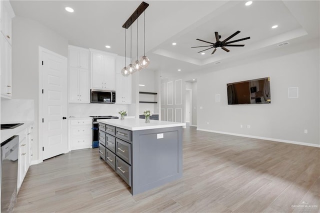 kitchen featuring appliances with stainless steel finishes, gray cabinetry, white cabinets, a raised ceiling, and a kitchen island