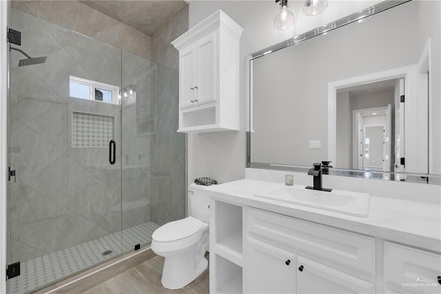 bathroom with toilet, a shower stall, and vanity