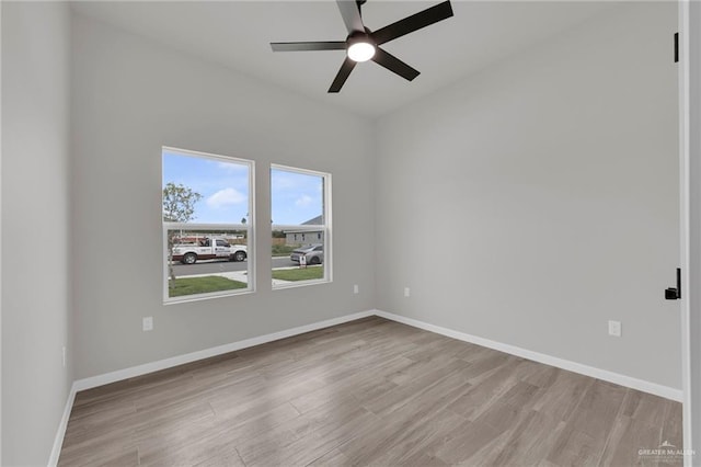 spare room with light wood-type flooring, a ceiling fan, and baseboards