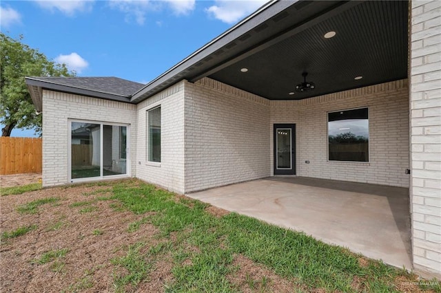 rear view of property with brick siding, a patio, fence, and ceiling fan