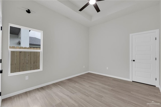 spare room featuring a ceiling fan, wood finished floors, baseboards, and a raised ceiling