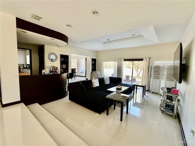 living area with light tile patterned floors, visible vents, a tray ceiling, and recessed lighting