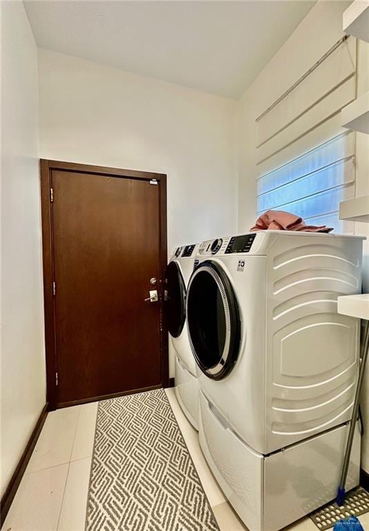 clothes washing area with laundry area, washer and clothes dryer, and light tile patterned flooring