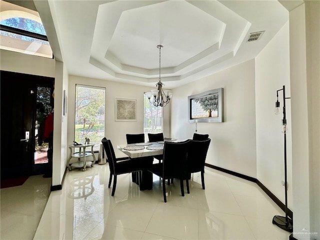 dining area featuring light tile patterned floors, visible vents, baseboards, a tray ceiling, and a notable chandelier